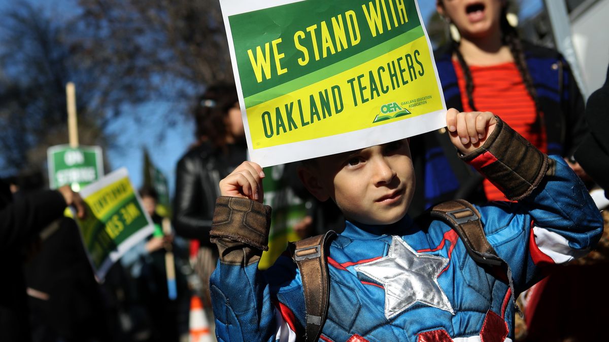 A child holds a sign that reads "We Stand With Oakland Teachers" during a 2019 protest outside of Manzanita Community School.
