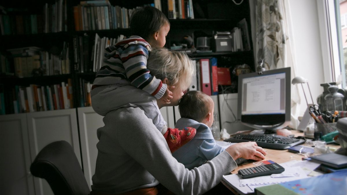 Mother working at home on the pc, with her children doing multi-tasking work.