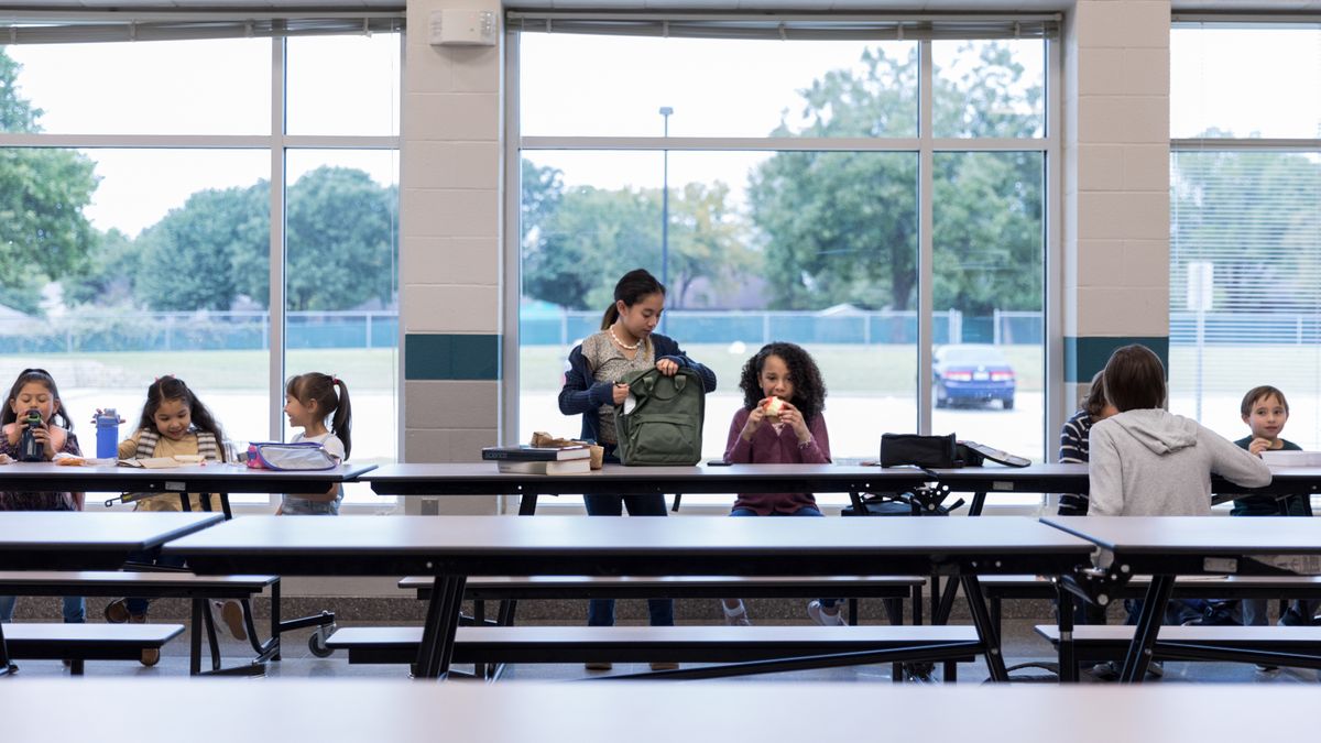 Group of students eating lunch in school cafeteria.