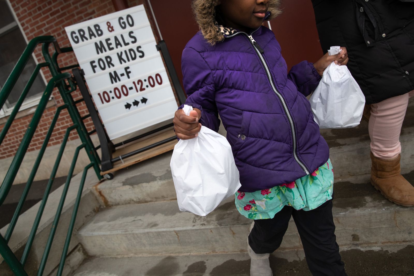 A student carries home bagged meals given out as part of Stamford Public Schools' "Grab and Go Meals for Kids" program, which is part of the city's response to the coronavirus pandemic on March 17, 20