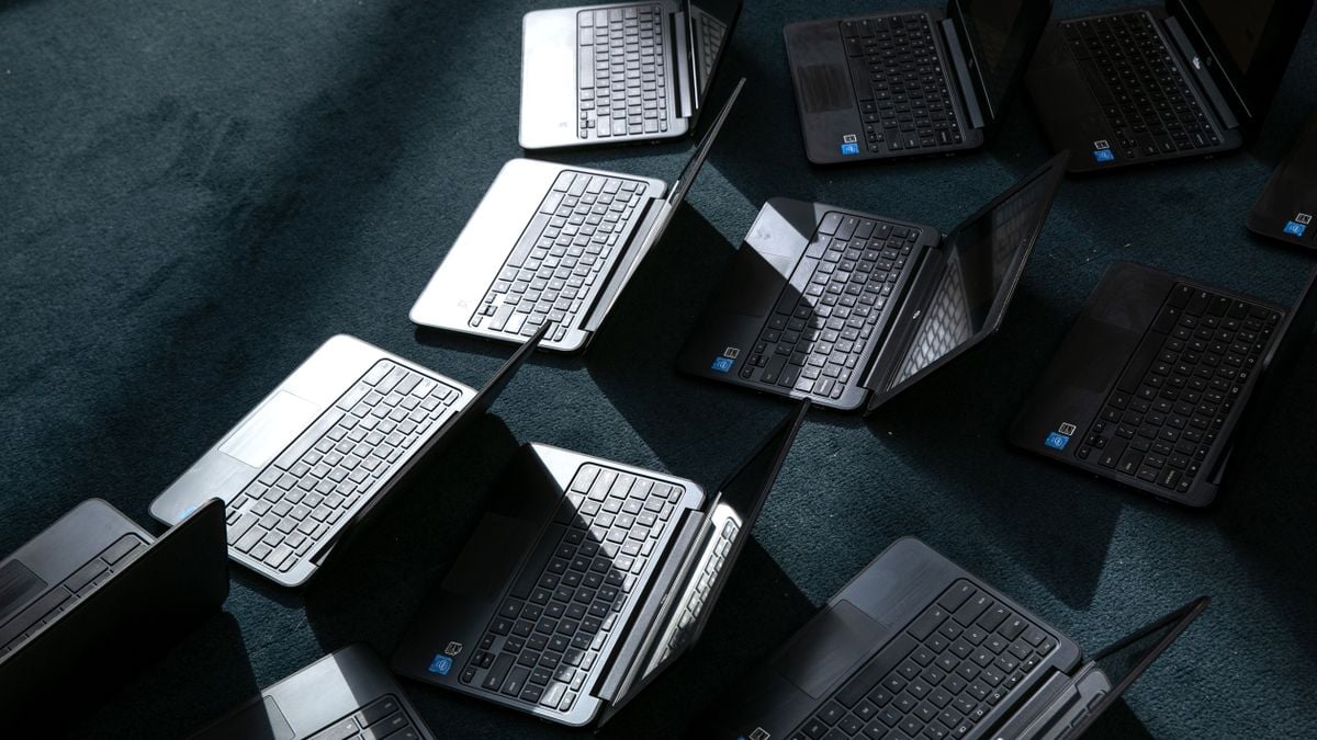 A group of Chromebooks lie open on the floor after being cleaned.