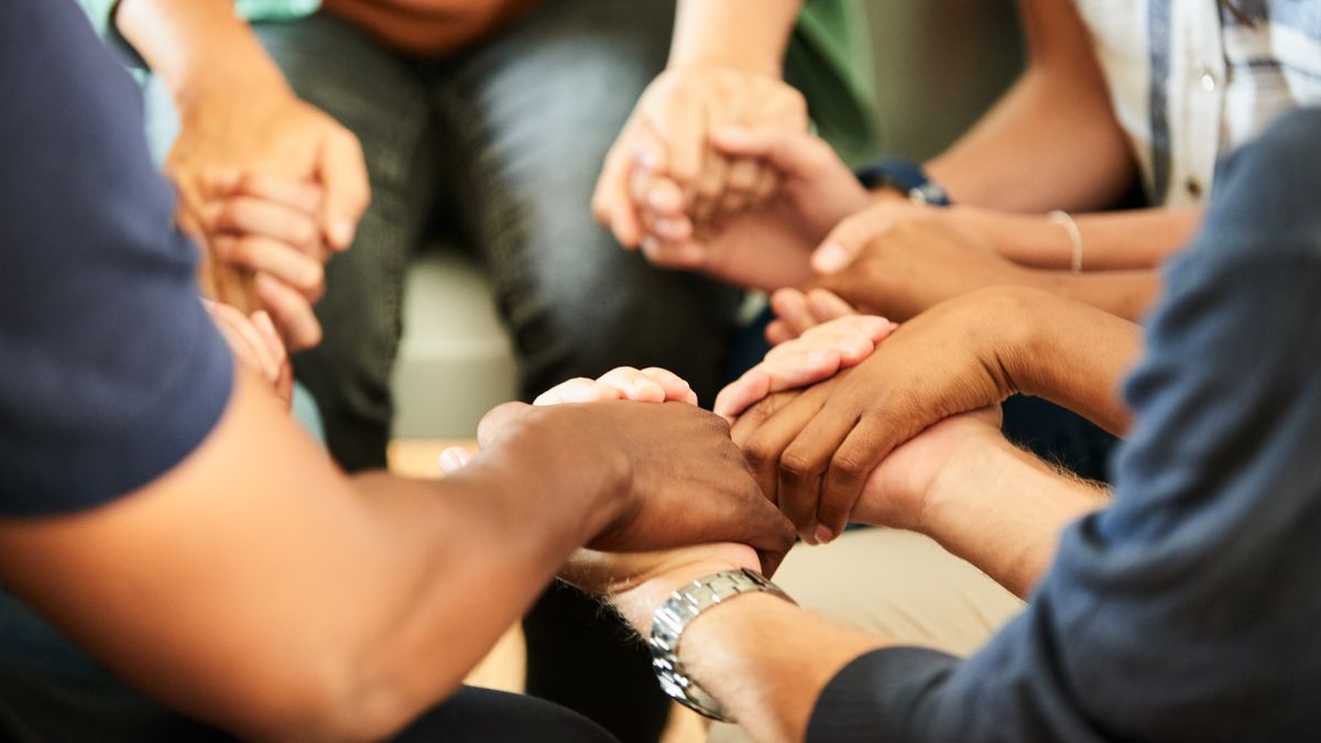 A close-up shot of hands in prayer, featuring a multiethnic group of people.