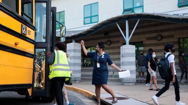 The assistant principal of Long Branch Elementary School greets students as they walk off the school bus in Arlington, Virginia.