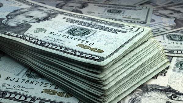 A stack of $20 U.S. bills lay on top of a scattering of more $20 bills.