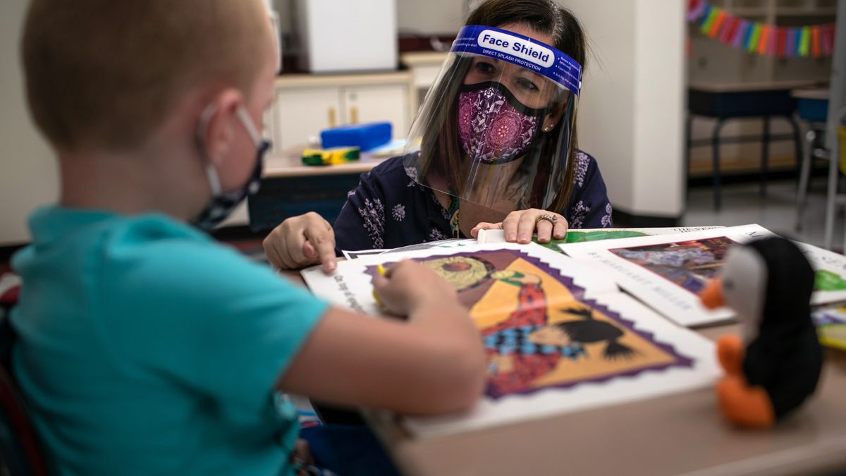 Teacher Elizabeth DeSantis, wearing a mask and face shield, helps a 1st grader during reading class at Stark Elementary School on Sept. 16, 2020 in Stamford, Connecticut.